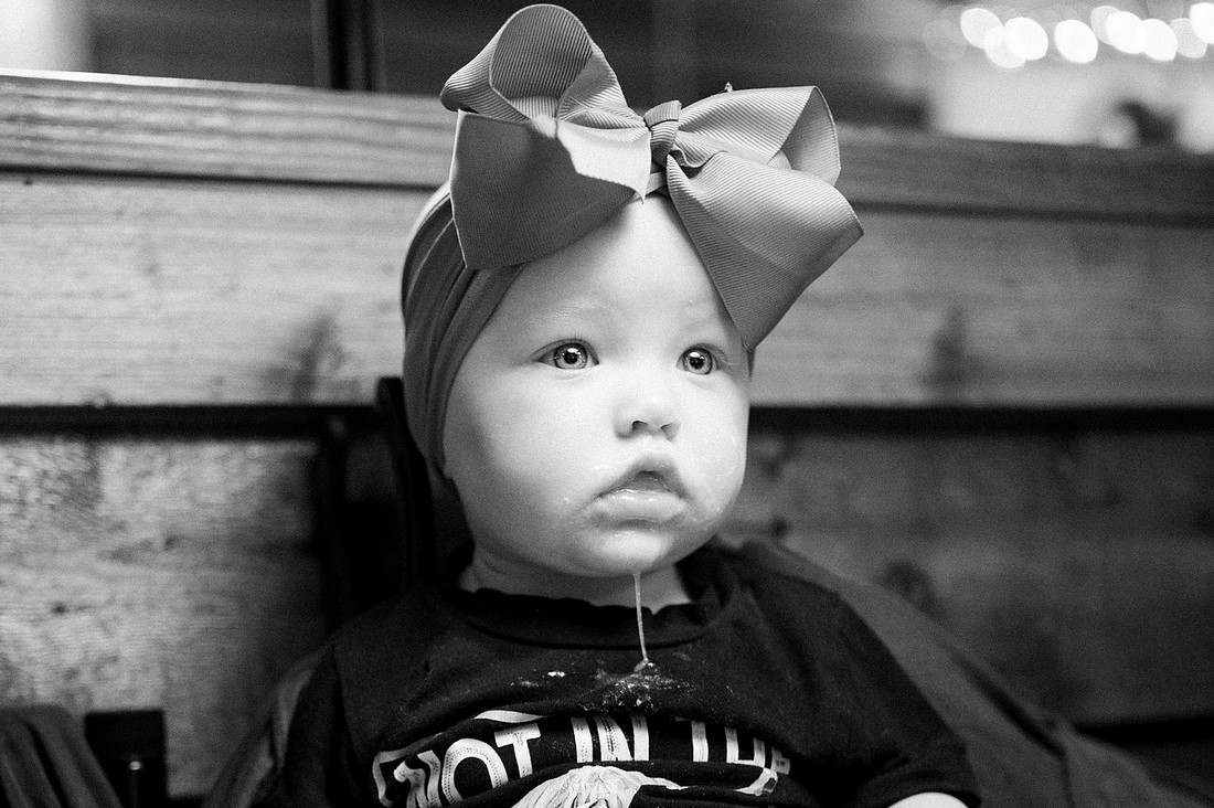 Baby wearing a large bow in a candid black and white portrait