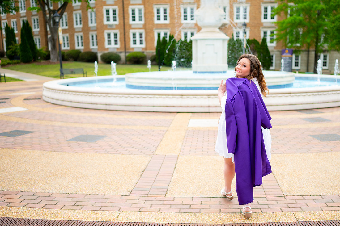 Graduate looking back while walking across a university courtyard