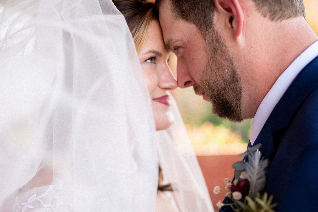 Bride and groom sharing a quiet moment beneath her veil