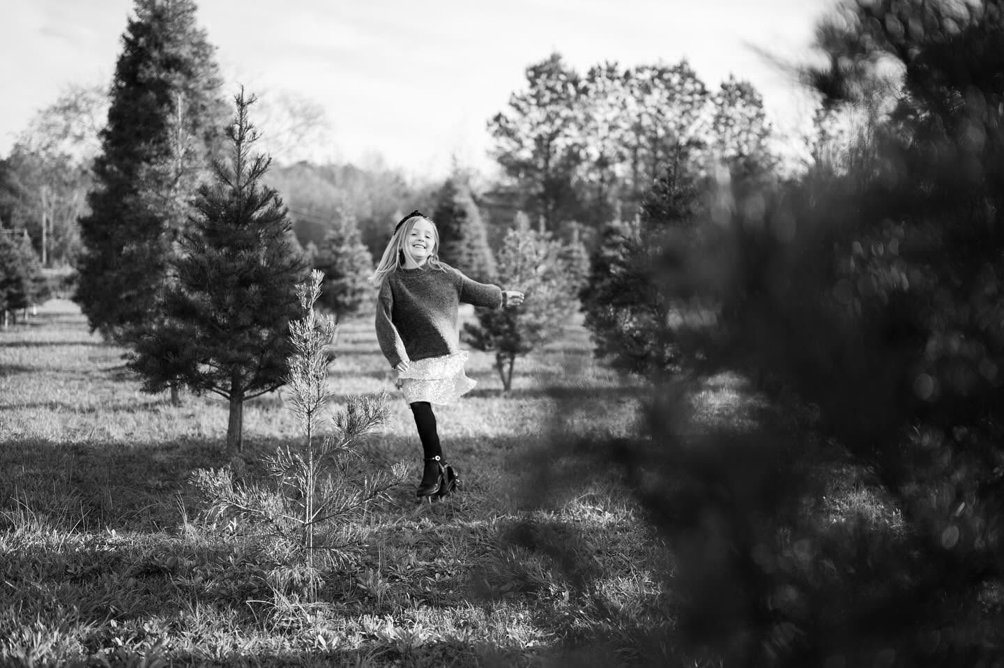 Child running through a tree farm in black and white