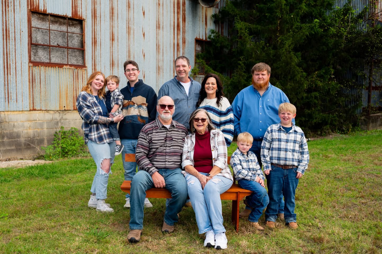 Extended family gathered for a portrait beside a rustic building