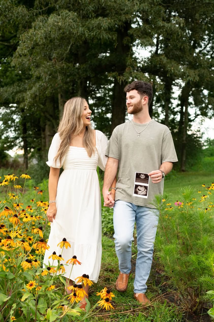 Expecting couple walking hand in hand through wildflowers