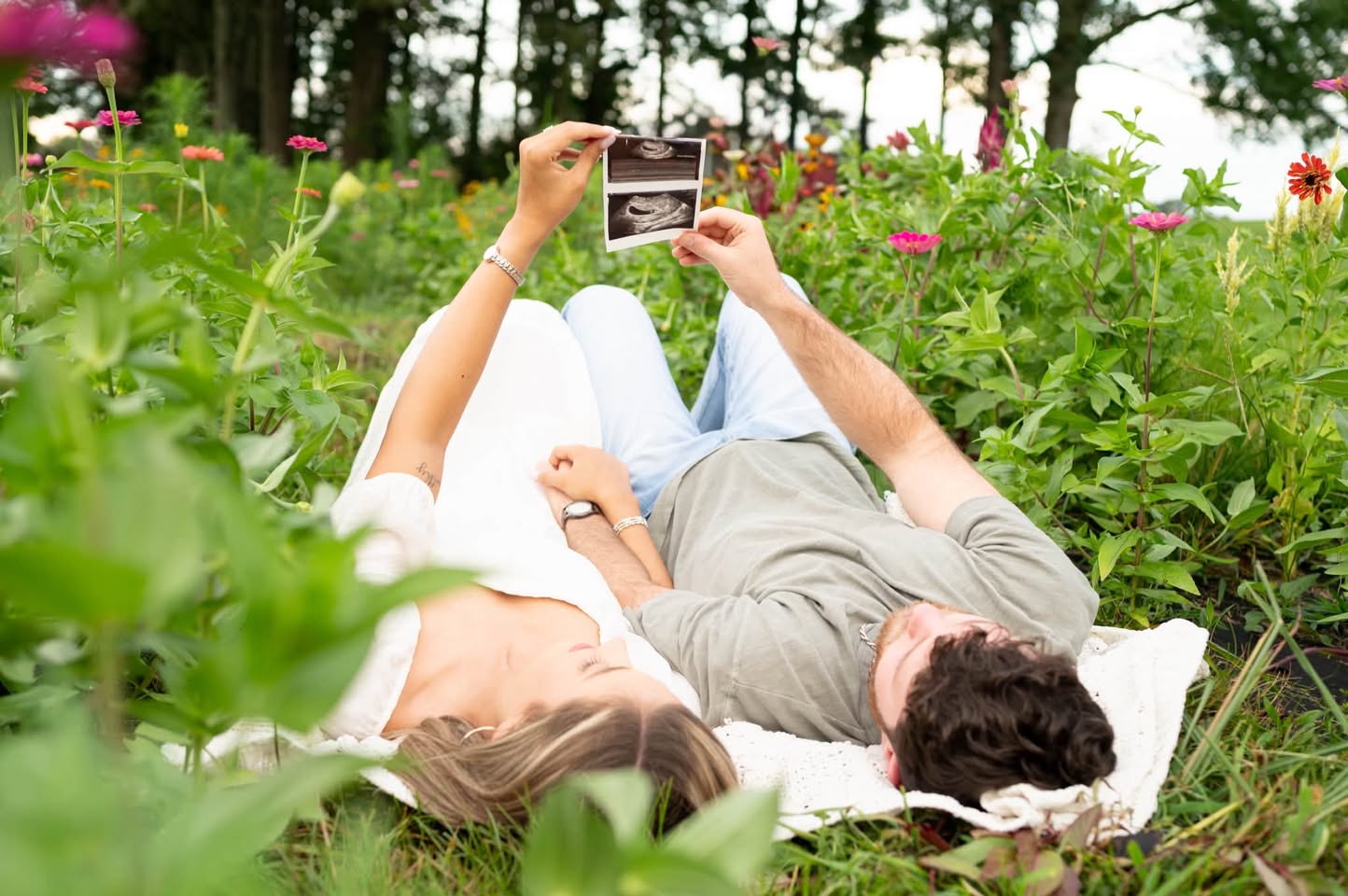 Expecting couple relaxing together among colorful wildflowers