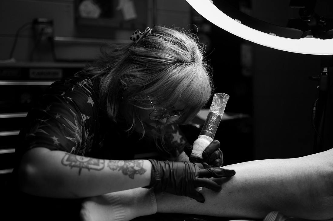 Tattoo artist working beneath a studio light