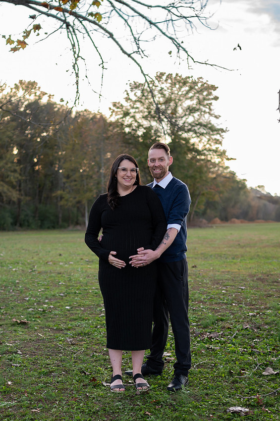 Expecting couple standing together in an open field