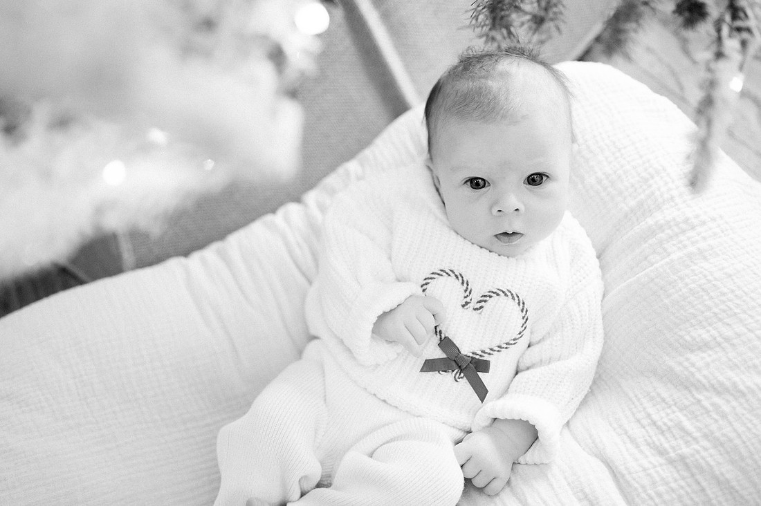 Baby seated among soft white blankets