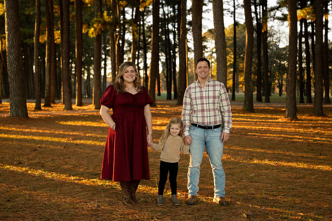 Family of three standing in warm evening light